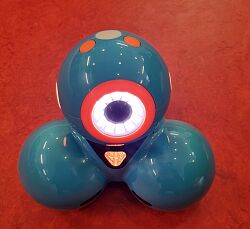 Der Roboter besteht aus drei runden Teilen und ist hellblau. Ein großer weiß leuchtender Kreis zeigt Gesicht und Augen.
