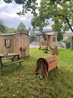 Holzpferd mit Stall und Bauwagen im Hintergrund - einige der Abenteuerspielstationen, welche die Kita Schiessrain über den Lahrer Stadtgulden anschaffen und 2024 endlich aufstellen konnte 