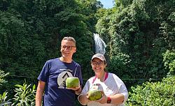 Markus Ibert mit Alajuelas Bürgermeisterin Sofia Gonzalez vor einem Wasserfall zwischen Bäumen in Costa Rica