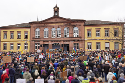 Blick auf das Rathaus II, ehemals Luisenschule, mit der Bühne davor und Menschen, die auf die Bühne blicken. 