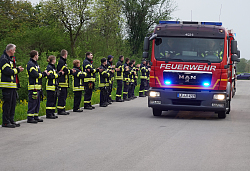 Feuerwehrmänner stehen Spalier während die Feuerwehrfahrzeuge in die Feuerwache einfahren