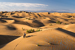 In den weitläufigen Dünen der Wüste Gobi ist ganz klein Thomas Schenker auf seinem Mountainbike fahrend zu erkennen. 