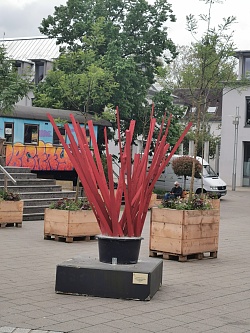 Sigles Werk "Einschlag/Auswux" besteht aus splittrigen, rot angemalten Holzstäben, die schräg gen Himmel zeigen.