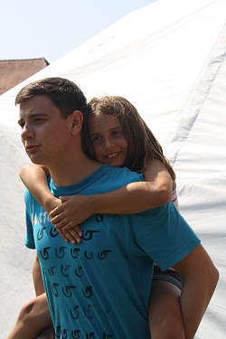 Das Bild zeigt einen Jugendlichen, der ein Mädchen Huckepack trägt.