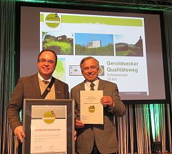 Das Bild zeigt den Präsidenten des Deutschen Wanderverbands, Dr. Hans-Ulrich Rauchfuß (rechts), der  dem Seelbacher Bürgermeister Thomas Schäfer (links) die Urkunde überreicht.