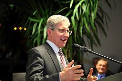 OB Dr. Müller steht an einem Rednerpult vor einem Mikrophon und spricht beim Deutsch-Kanadischen Wirtschaftsklub