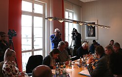 Bei der Jahrespressekonferenz sitzen Oberbürgermeister Dr. Wolfgang G. Müller, Erster Bürgermeister Guido Schöneboom und Bürgermeister Tilman Petters im Rathaus Lahr mit Journalisten und Vertretern der Verwaltung am Tisch und berichten über die wichtigen Vorhaben und Themen des Jahres. Im Hintergrund stehen zwei Kameraleute mit ihren Kameras, die auf die Bürgermeister gerichtet sind.
