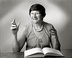 Schwarz-Weiß-Bild von Gertrudis Weiß, die an einem Tisch sitzt und vor sich ein Buch liegen hat