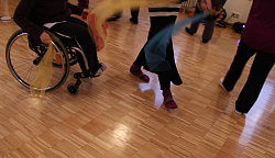 Eine Frau im Rollstuhl tanzt gemeinsam mit anderen Frauen mit Tüchern