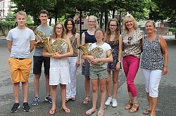 Gruppenbild der Preisträger des Bundeswettbewerbs Jugend musiziert mit ihren Lehrkräften. Die Hornisten halten ihr Instrument in den Händen. 