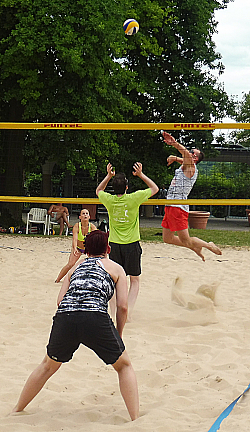 Spielszene aus dem Finale des Beach Fun Cups. Ein Spieler schmettert den Ball übers Netz. Die Gegner lauern auf die Annahme. 
