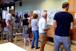 Der Workshop zur Ortsmitte Sulz ist auf reges Interesse gestoßen. In der Sulzer Grundschule stehen mehrere Personen vor Stellwänden mit Plänen der Sulzer Ortsmitte. Gemeinsam diskutieren sie über die Möglichkeiten der Gestaltung. 