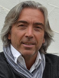 Porträt von Autor Harald Rudolf, der in der Mediathek Lahr liest.
Rudolf trägt ein graues Jacket, ein weißes Hemd und einen Schal. Er hat halblanges leicht ergrautes Haar und einen Dreitagebart. 