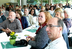 Das Bild zeigt das Publikum bei der Einweihungsfeier des Erweiterungsbaus der Otto-Hahn-Realschule Lahr. Die Gäste sitzen an Tischen und blicken nach vorne. 