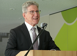 Bei der Einweihungsfeier des Erweiterungsbaus der Otto-Hahn-Realschule Lahr steht Oberbürgermeister Dr. Wolfgang G. Müller am Mikro mit dunkelgrauem Anzug und Kravatte.