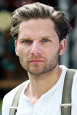 Junger Mann mit blauen Augen, schaut ernst in die Kamera