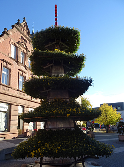 Eine Chrysanthemen-Pagode nach asiatischem Vorbild mit fünf übereinander gestapelten geschwungenen Dächern. Blauer Himmel im Hintergrund.