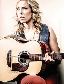 In der Lahrer Reihe Songs 'n' Singers tritt Amanda Rheaume auf.
Die Sängerin mit blonden Locken posiert mit Gitarre, trägt eine ärmellose Jeansweste und eine rote Jeans. Sie hat auf ihrem Knie eine Gitarre. 