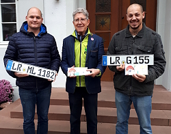 Die Stadt Lahr wird von LR-Kennzeichen dominiert. 

Markus Lutterer, Oberbürgermeister Dr. Müller, Adriano Sammartino von links stehen auf der Treppe des Rathauses und halten jeweils ein LR-Kennzeichen in die Kamera. 
