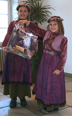 Beim Entdeckerquiz der Stadt Lahr zogen die zwei Blumenmädchen der Chrysanthema die Gewinner.
Beide Mädchen haben ihr lilafarbenes Blumenmädchenkleid an.
Die Größere von beiden mit Zoph hält eine durchsichtige Box mit den Karten, währen die Kleinere mit blonden Haaren eine Gewinnerkarte zieht. Beide lächeln in die Kamera. 