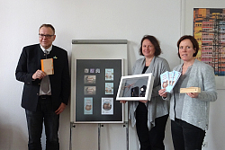 Im Bild links sieht man den Ersten Bürgermeister Guido Schöneboom, Friederike Ohnemus in der Mitte, rechts Martina Mundinger. Sie halten die verschiedenen Kommunikationsmedien und Shop-Artikel in den Händen. 