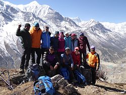 Auf dem Bild sieht man Günther Wolf-Melcher zusammen mit seinen Begleitern auf einem Berg des Annapurna-Massivs. Im Hintergrund eine wunderschöne Bergkette. Die Bergsteiger strahlen mit der Sonne um die Wette.