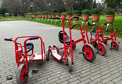 Im Stadtpark Lahr gibt es neue Fahrzeuge für Kinder. 
Auf dem Bild stehen Dreirad, Roller und Laufrad in rot aufgereit nebeneinander. Im Hintergrund sieht man Küpel mit noch nicht erblühten Tulpen. 