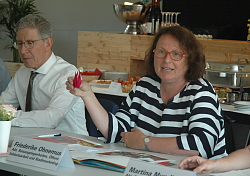 Chrysanthema PK von links Dr. Wofgang G. Müller und Friedericke Ohnemus. Frau Ohnemus hält eine Origami-Blüte in rot. 