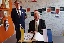 MP Kretschmann zu Besuch in Lahr. Blick auf das goldene Buch, im Monent, als Kretschmann schwungvoll in großen Buchstaben unterschreibt. 