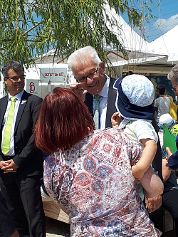 MP Kretschmann zu Besuch in Lahr. Er winkt einem Kind zu, das von einer Dame im Arm gehalten wird. 