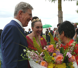 OB Dr. Müller und Chrysanthemenkönigin Lea Johanna I. übergeben lächelnd einen Blumenstrauß an Frau Herrenknecht. 