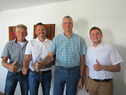 Vier Männer lächeln in die Kamera und halten jeweils den Daumen nach oben