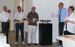 Der Förderverein übergibt ein neues Exponat.&#13;&#10;Von links stehen Thomas Joachims,Rechner des Fördervereins, erster Vorsitzender Jürgen Frank und zweiter Vorsitzender Klaus Ohnmacht, dann folgt auf einem Sockel die silberne Hülse. Rechts davon stehen Guido Schöneboom und Museumsleiterin Gabriele Bohnert. 