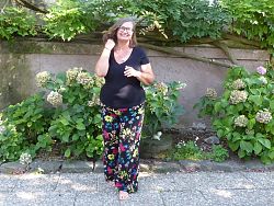 Landesgartenschau-Führerin Caroline Burkart führt den eigenen Garten vor. Frau steht vor begrünter Gartenmauer.