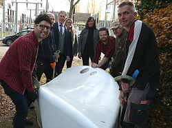Ein weißer Waver steht in der Mitte und wird von mehreren Herren angehoben, mit dabei Oberbürgermeister Dr. Wolfgang G. Müller und Ulrike Vath von der Firma Grünkultur. 