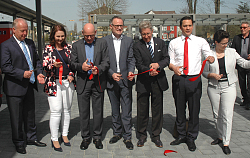 Einweihung des Bahnhofs - Ehrengäste durchschneiden ein rotes Band