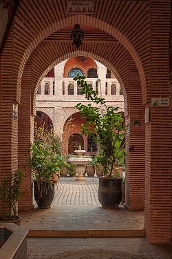 Das Bild zeigt einen Innenhof im Süden von Marokko, fotografiert durch einen Torbogen am Eingang