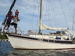 Großaufnahme der Segelyacht, das Ehepaar Flum steht strahlend vorne auf dem Bug, Sohn Thorben sitzt bei Papa auf den Schultern