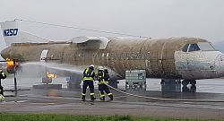 Zwei Feuerwehrleute der Stadt Lahr stehen vor einem Flugzeug und versuchen einen vermeintlichen Brand bei einer Übung mit einem Feuerwehrschlauch zu löschen. 