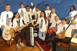 Die Musiker der Band stehen zu einer Gruppe zusammen, haben ihre Instrumente in den Händen und sind mit weißen Hemden und Kravatte gekleidet. 