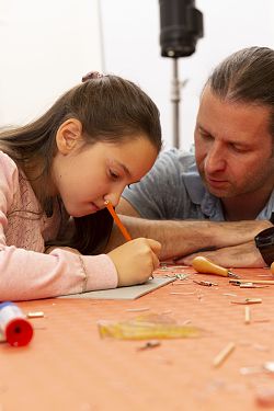 Das Bild zeigt ein Mädchen zusammen mit ihrem Papa beim Basteln im Mitmach-Atelier