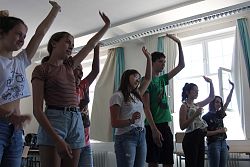 Das Bild zeigt die Kinder während der Probe. Sie stehen etwas versetzt, die Augen nach vorne gerichtet. Sie heben alle den linken Arm nach oben.