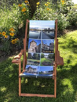 Zu sehen ist der neue, nachhaltig hergestellte Liegestuhl mit Motiven der Stadt Lahr wie Seepark, Stadtmuseum, Stadtpark und Storchenturm. Er besteht aus massivem rot-braunen Buchenholz.