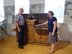 Zu sehen ist ein antikes Setzregal. Links steht der Spender des Objekts und ehemalige Setzer bernhard Bürkle, rechts Silke Höllmüller vom Stadtmuseum Lahr.