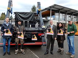Das Bild zeigt von links nach rechts: Martin Stehr vom Stadtplanungsamt, Patrick Schmidt vom BGL, Baubürgermeister Tilman Petters, Agnes Bruder vom BGL und Herbert Schneider, den BGL Betriebsleiter. Sie stehen auf dem Betriebshof des Lahrer BGL vor einem großen Fahrzeig, auf dem die Toter Winkel Aufkleber angebracht sind und halten jeweils einen solchen Aufkleber in den Händen.
