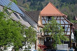 Ein Blick auf ein altes Fachwerkhaus im Schwarzwald, daneben steh ein Haus mit Solartechnik auf dem Dach. 