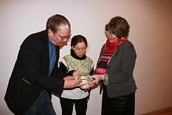 Auf dem Bild blicken von (von links) Thorsten Mietzner (Stadtarchivar), Elise Voerkel (Stadthistorikerin) und Gabriele Bohnert (Leiterin Bereich Stadtmuseum und Stadtarchiv) auf eine Vase und diskutieren über die Zeichnung auf der historischen Vase.