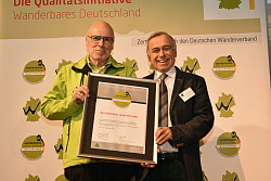 Das Foto zeigt zwei Männer. Ein Mann übergibt dem anderen eine Urkunde. Es handelt sich um die Auszeichnung des Wanderweg Geroldsecker Qualitätsweg.