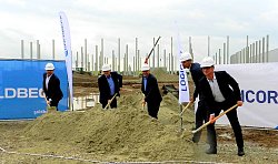Fünf Männer, darunter Oberbürgermeister Markus Ibert, stehen mit weißen Bauhelmen auf dem Kopf in Anzug und Hemd mit Schaufeln an einem großen Sandhaufen und stechen sie in den Sand.