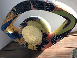 ein Kunstwerk bunt bemalt, gehauen aus einem Stein. Ein Oval, in der Mitte frei